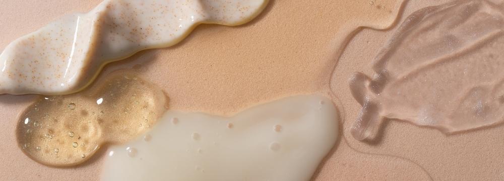 skincare products and serums spread on tan background