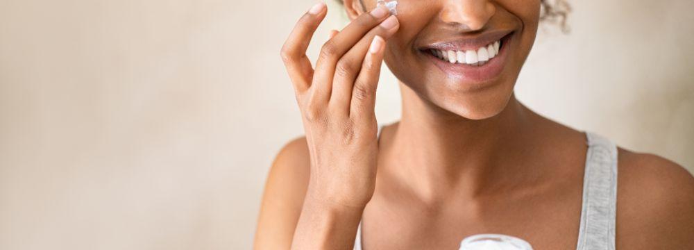 Woman applying cream to prevent acne scars