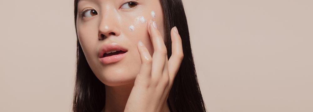 Woman putting moisturizer on cheek