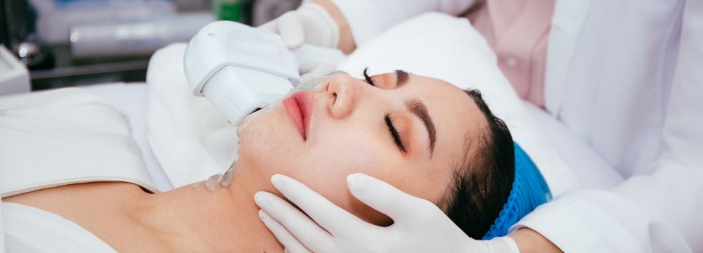 Woman with IPL laser on cheek by dermatologist with gloves on both cheeks