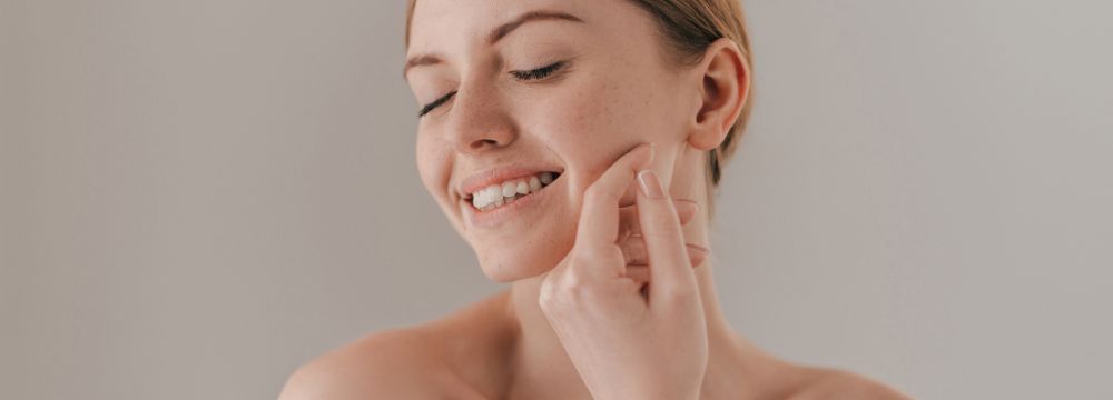 Woman touching face with hand while smiling