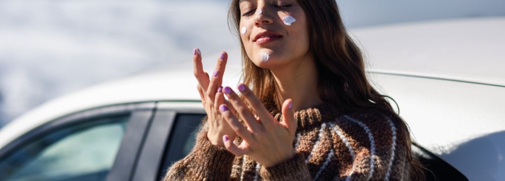Woman applying sunscreen dots on face before entering car