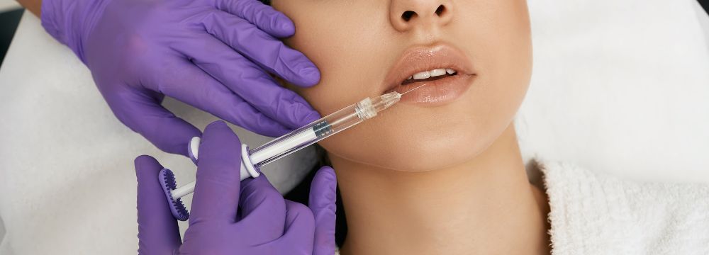 Woman receiving lip filler with needle by provider in purple gloves 