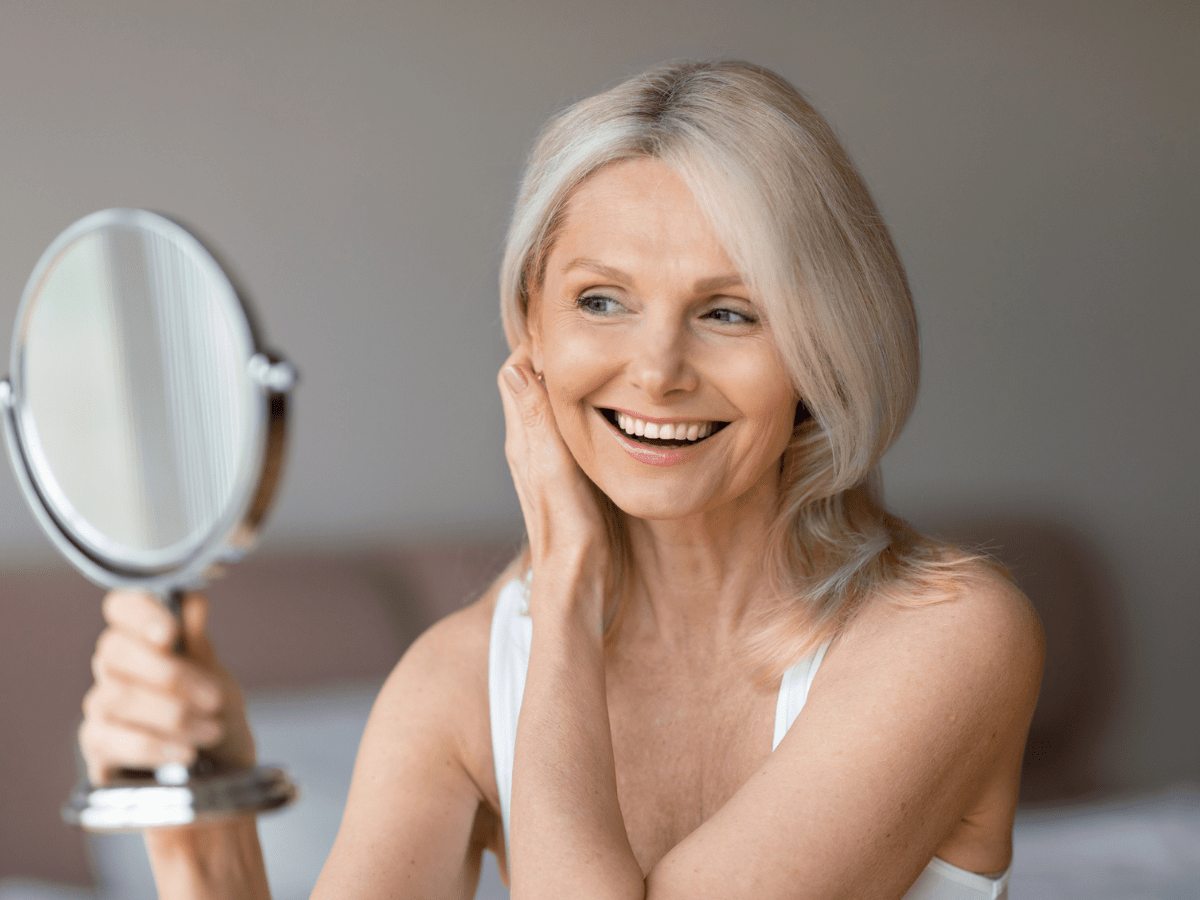 woman using handheld mirror to examine face